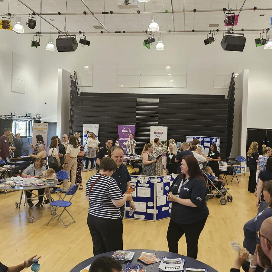 People standing around tables in a sports hall